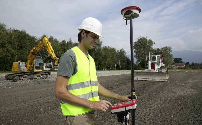 Surveyor on construction jobsite with GPS rover receiver 